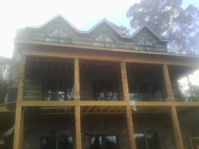 Dormers and porch framing on a large log home under construction — Roof Coating work by our crew in Hampshire
